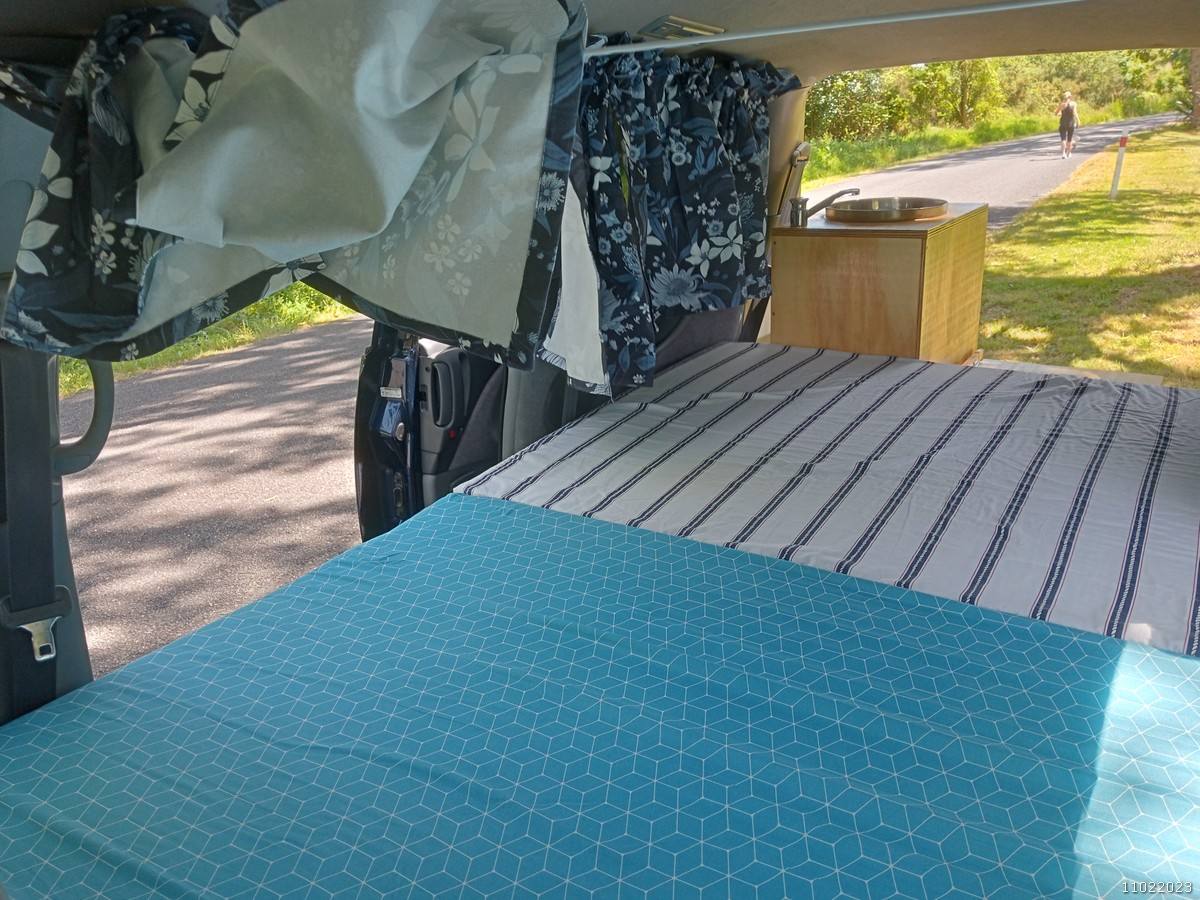 Inside the FDK492 campervan looking forward over the bed to the sink unit and the open side door