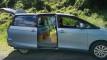 Blue 2006 Toyota Estima self-contained campervan for sale, side door and tailgate open on a grass verge