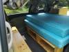 Side door open on the JTQ214 campervan, bed on its frame with storage space underneath