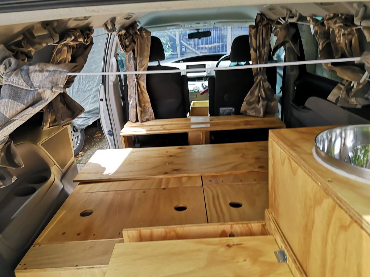 Inside the JTQ214 campervan looking forward over the plywood bed base to the sink unit and cab
