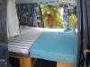 Inside the FDK492 campervan, bed made up with the side door open to the garden