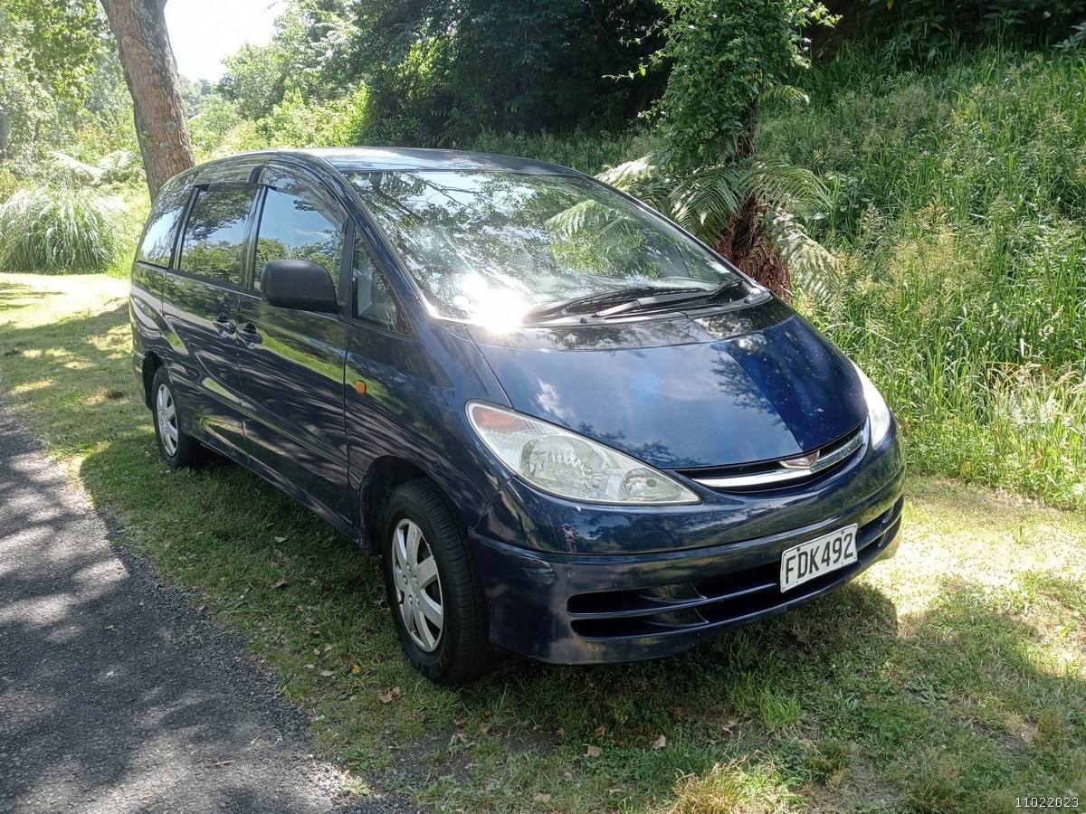 Dark blue 2000 Toyota Estima self-contained campervan for sale, front three-quarter view in dappled shade