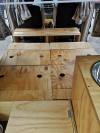 Plywood bed base of the KZR927 campervan laid out flat, with the bench across the back of the front seats