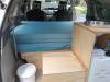 Inside the KHP570 campervan, mattress folded on the bed base beside the kitchen unit and rubbish bin