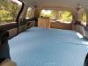 Inside the KHP570 campervan looking forward over the made-up bed to the kitchen unit