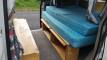 Side door open on the JBB773 campervan, bed made up with storage space below