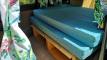 Bed on its plywood base in the DJR846 campervan with storage underneath and leaf-print curtains