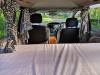 Inside the FPS382 campervan looking forward over the made-up bed to the front seats
