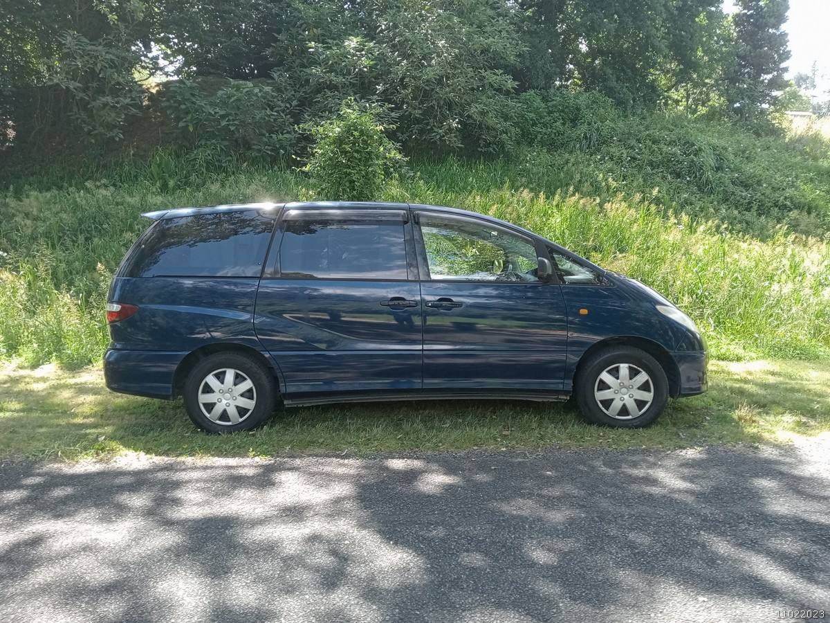 Side view of the dark blue Toyota Estima campervan FDK492 parked on a country road
