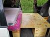 Plywood bed base of the JDP67 campervan laid out, with the mattresses folded to one side