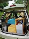 Tailgate open on the EZQ488 campervan, showing the bed, kitchen unit with sink and the water containers