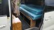 Side door open showing the campervan's double bed, the storage drawers underneath and the wooden step box