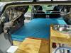 Inside the JTQ214 campervan with the side door open, bed, sink unit and plywood table