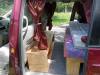 Inside the red JAK653 campervan, bed on one side with plywood storage boxes on the other