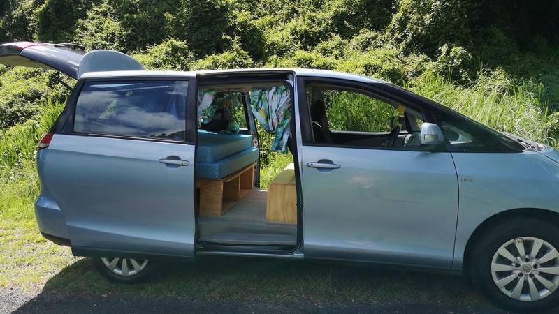 Blue 2006 Toyota Estima self-contained campervan for sale, side door and tailgate open on a grass verge