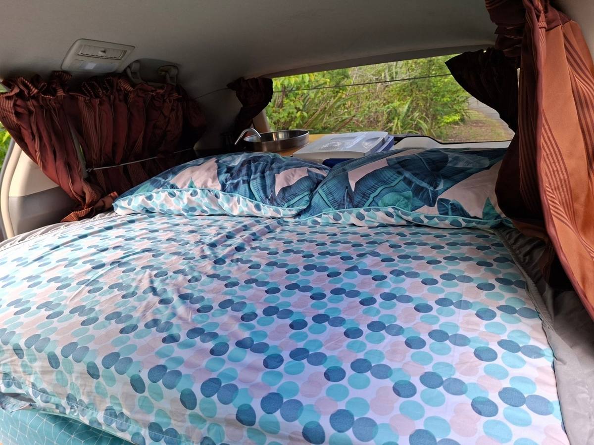 Bed made up with a duvet in the JAK653 campervan, looking out through the rear window