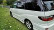 Rear three-quarter view of the white Toyota Estima campervan FJD528, parked on grass