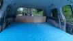 Inside the EYC409 campervan, full-width bed made up looking towards the kitchen bench