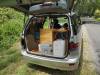 Tailgate open on the KBZ76 campervan, showing the bed, portable toilet, sink unit and water container