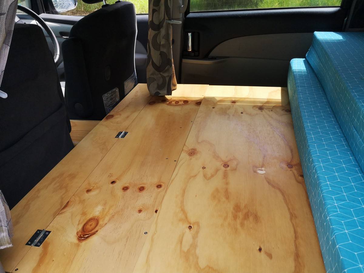 Plywood bed base of the JTQ214 campervan laid out flat, mattress folded to one side