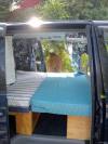 Side door open on the dark blue FDK492 campervan, double bed made up with the ferns behind